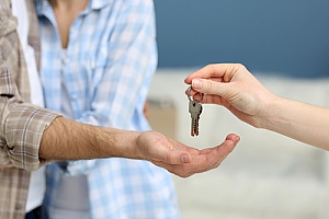 a real estate agent giving the keys of a home to brand new homeowners