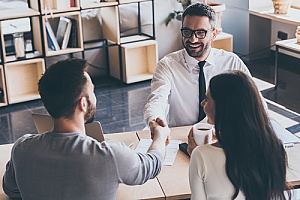 real estate agent shaking hands with a new couple