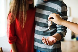 a real estate agent closing out the home buying process by giving the keys to a couple