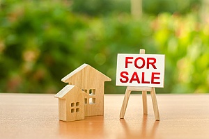 a wooden house next to a for sale sign representing the home selling process