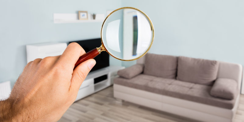 person holding a magnifying glass to inspect a home