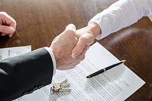 a man shaking hands with a home buyer after a for sale by owner house sale
