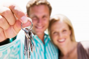 a couple holding keys to their new home after being in escrow