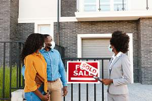 A couple and a real estate listing agent standing outdoor