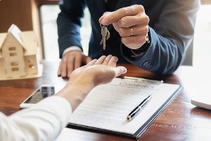A listing agent handing key to a new home owner