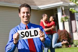 A listing agent holding a placard that has Sold written on it