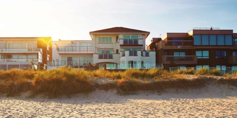 three large beach homes shown on a beach front that can be invested in for profit.jpg